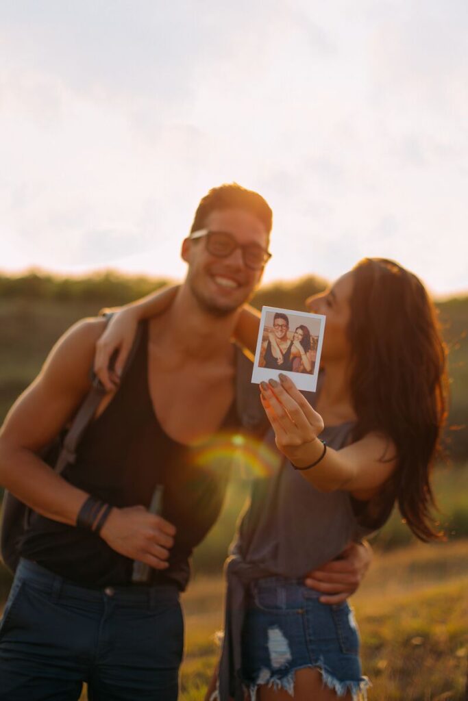 A couple embracing in the sunset, holding a polaroid photography